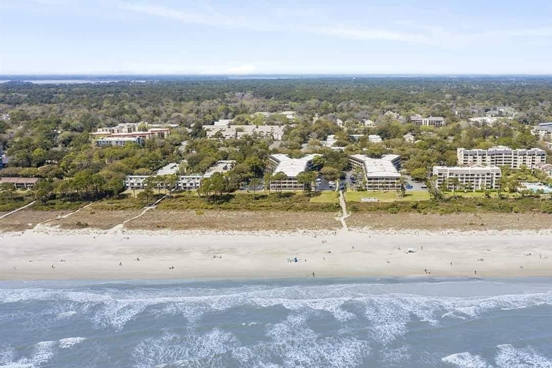 Ett hotell vid kusten med flera byggnader, en sandstrand och utsikt över havet.