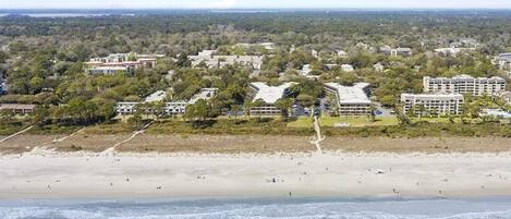 Ett hotell vid kusten med flera byggnader, en sandstrand och utsikt över havet.