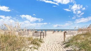 A sandy beach with a wooden fence, beach umbrellas, and sparse vegetation. - Beautiful Ocean View - Walk to Coligny (Hilton Head Island)