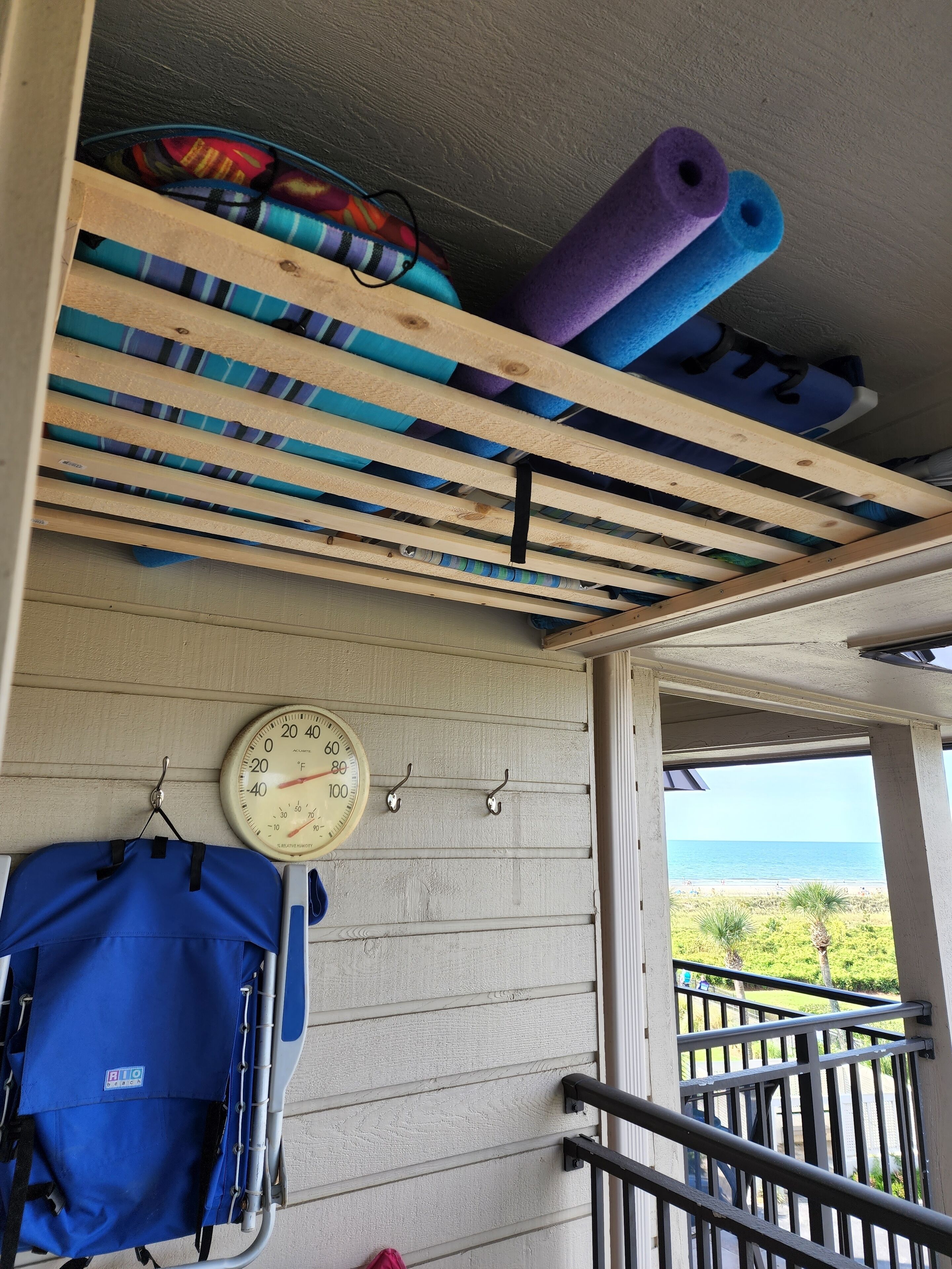 Una habitación con literas, un reloj de pared, una bolsa azul y vistas al océano.