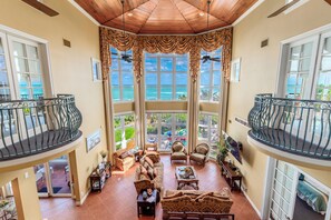 Ein großzügiger Wohnbereich mit Meerblick, ausgestattet mit Sofas und Sesseln, sowie ein Balkon mit Geländer.