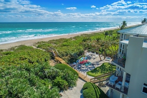 Une propriété située en bord de mer, dotée d’une terrasse en bois, de chaises de plage et de kayaks.