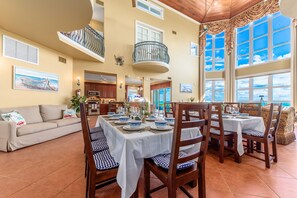 A spacious dining area with a high ceiling, large windows, and a balcony. - Chateau de la Mer:  Gated Fla Beach Estate w/ heated pool, hot tub, elevator.   (Jensen Beach)