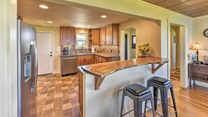 A modern kitchen with a central island, wooden cabinets, and a stainless steel refrigerator. - Waterfront Home ~ 6 Mi to Olympic National Park! (Port Angeles)