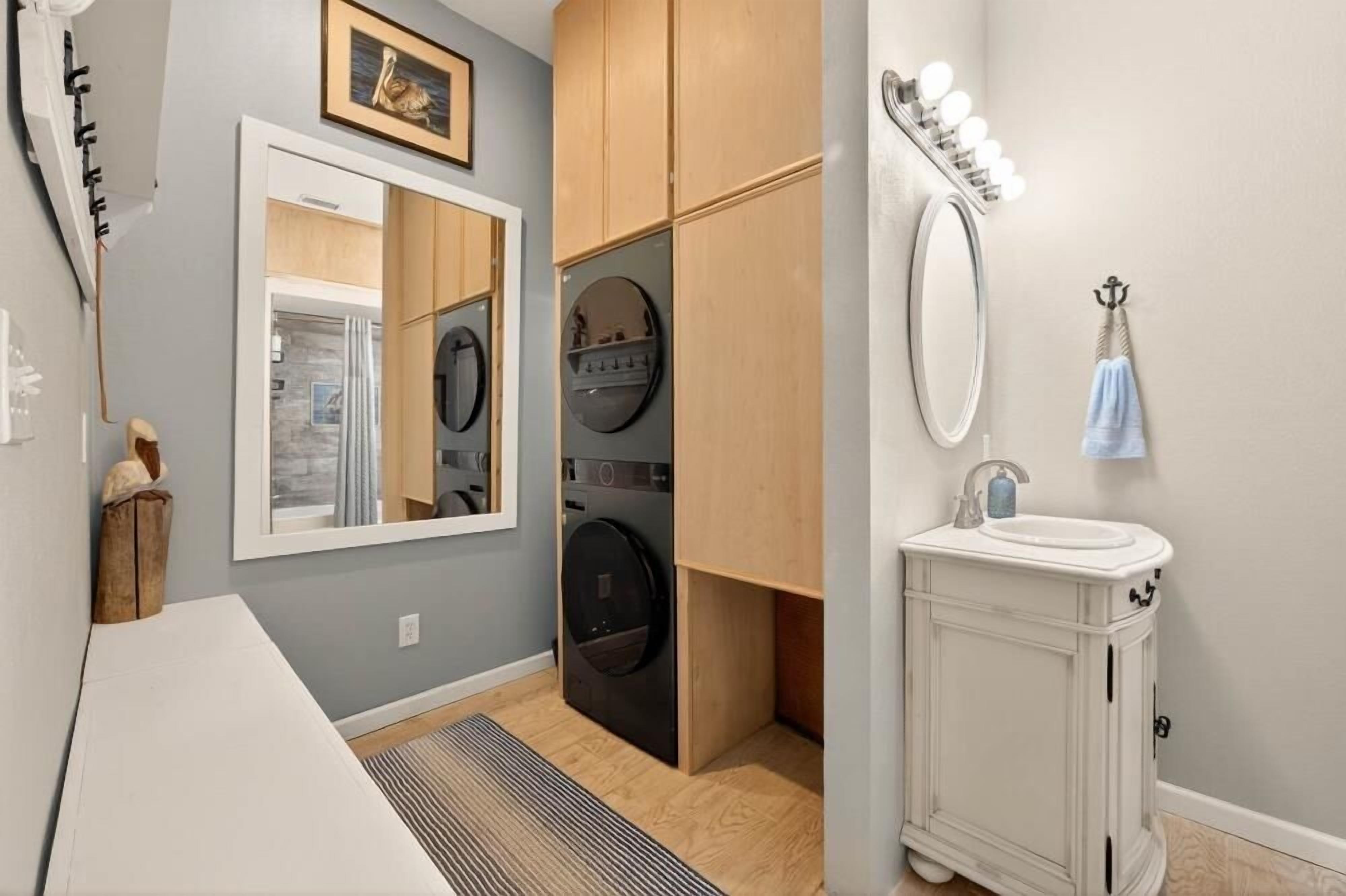 Une buanderie équipée d’un lave-linge, d’un sèche-linge et d’un miroir avec éclairage.