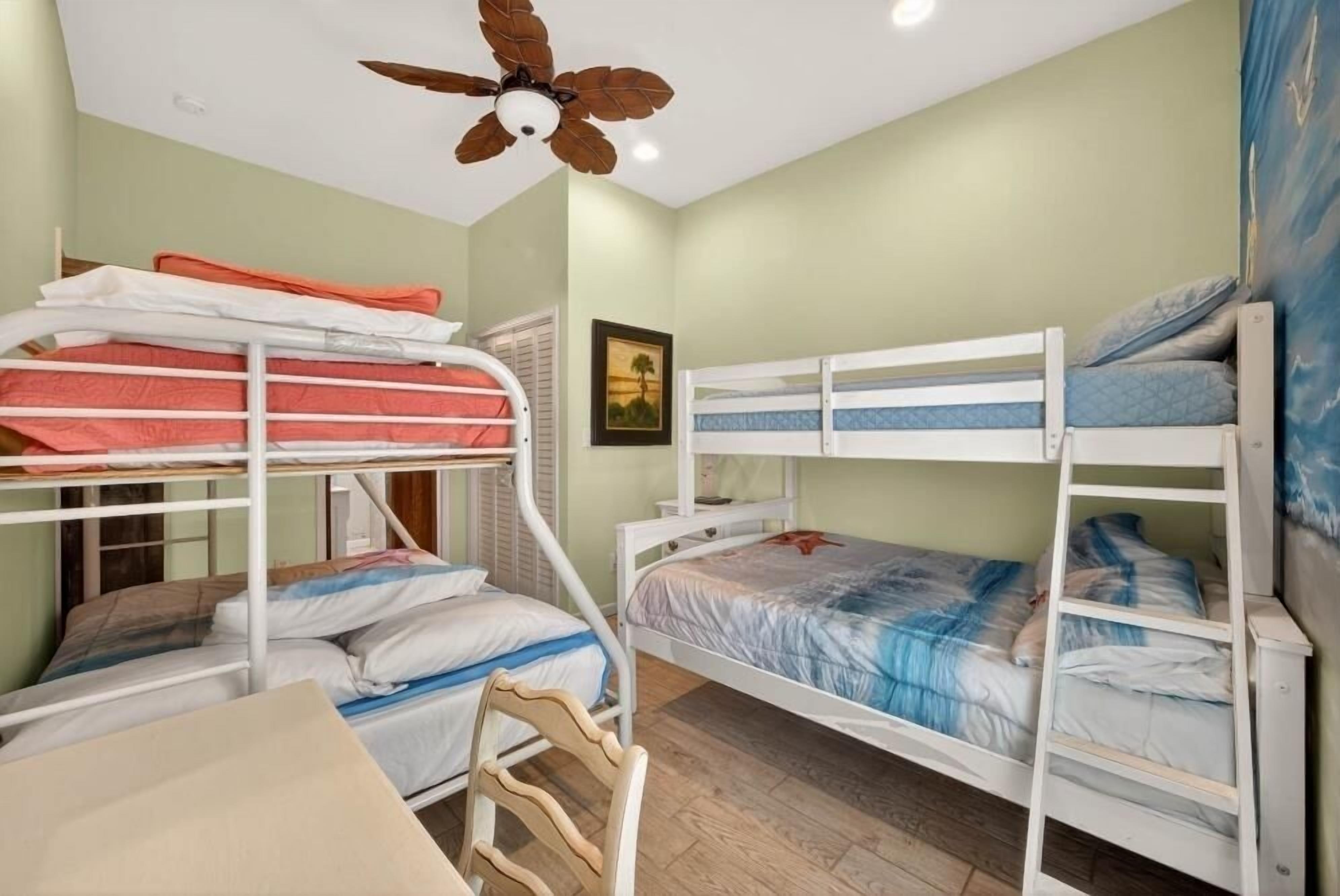 Un dormitorio con literas, un ventilador de techo y un cuadro en la pared.