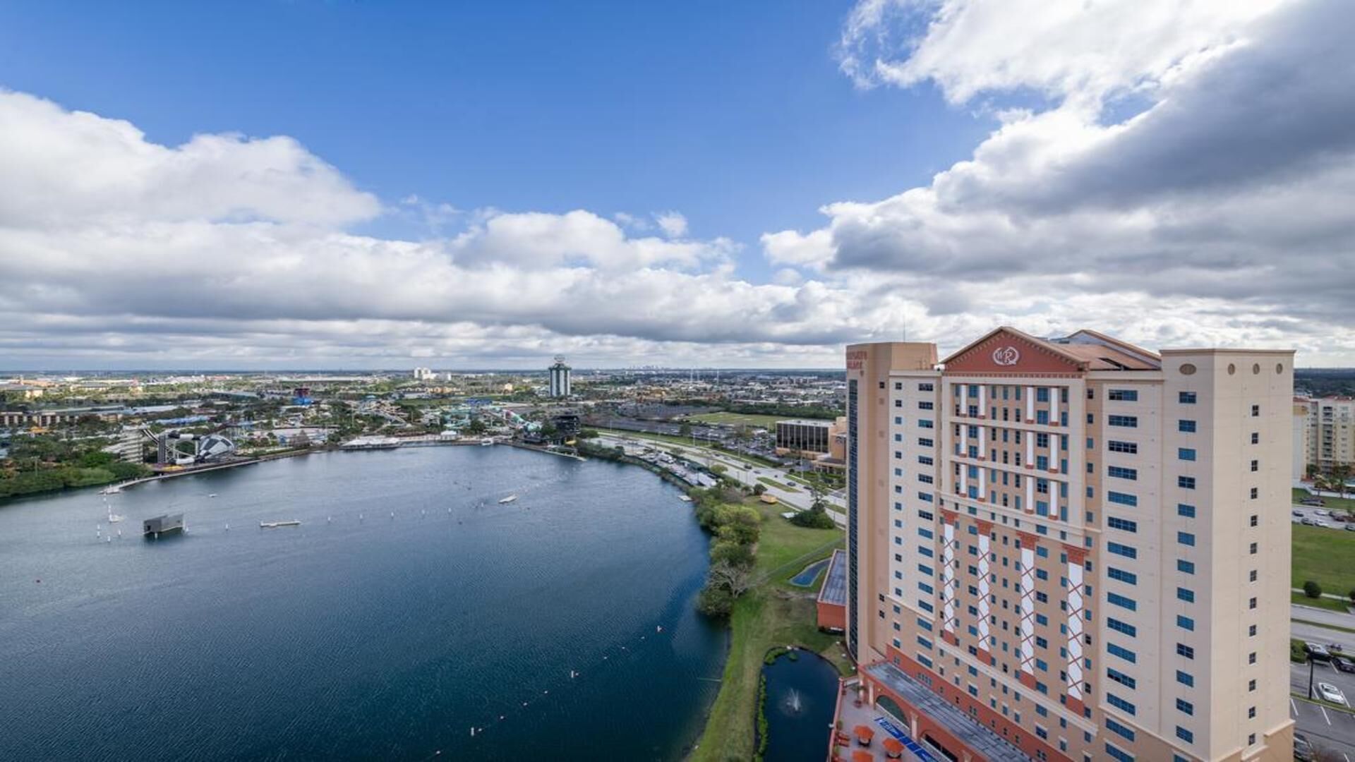 A high-rise hotel with a view of a large body of water and a distant cityscape.