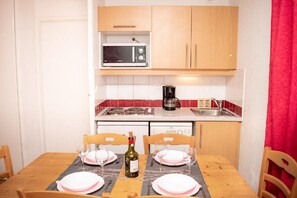 A compact kitchen with a microwave, coffee maker, and a dining table set for two. - Wifi, Ground floor, swimming pool, balcony, parking, tv, ski locker, 39m², Puy-Saint-Vincent (Puy-Saint-Vincent)