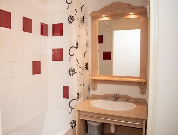 Ein Badezimmer mit einer Badewanne, einem Holzkosmetikschrank mit Waschbecken und einem Spiegel.