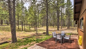 An outdoor patio with a table and chairs, surrounded by a forest. - Flagstaff Home w/ Back Deck - 5 Mi to Downtown (Flagstaff)