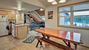 A spacious kitchen with wooden cabinets, a central island, and a large dining table with benches. - Lakefront Home w/ Seasonal Dock - 2 Mi to Skiing! (Wautoma)
