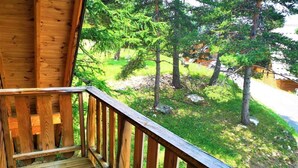 Um deck de madeira com guarda-corpo, com vista para uma área gramada com árvores.
