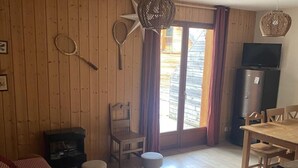 Um quarto com painéis de madeira, um sofá, uma mesa, um banco e uma televisão.
