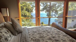 A bedroom with a large bed, a view of the sea, and a wooden window frame. - Charming Annapolis WaterVIEW Home (Annapolis)