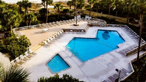Ein Poolbereich mit zwei Pools, Liegestühlen und Palmen.
