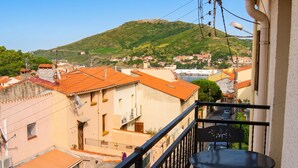 Un balcon donnant sur une ville située sur une colline, avec une table et une chaise.