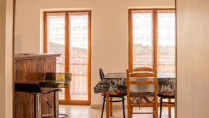 Un coin repas comprenant une table et des chaises, un buffet en bois et deux fenêtres ornées de rideaux à motifs.