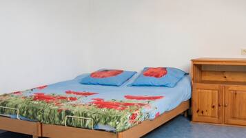 Une chambre à coucher avec un lit en bois, un matelas bleu et une couvre-lit à motifs floraux.