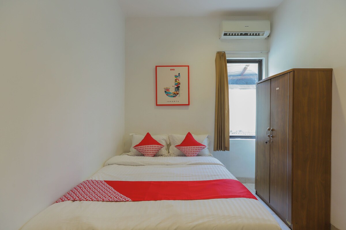 Een hotelkamer met een bed, een kledingkast, een raam met gordijnen en een wandairconditioner.