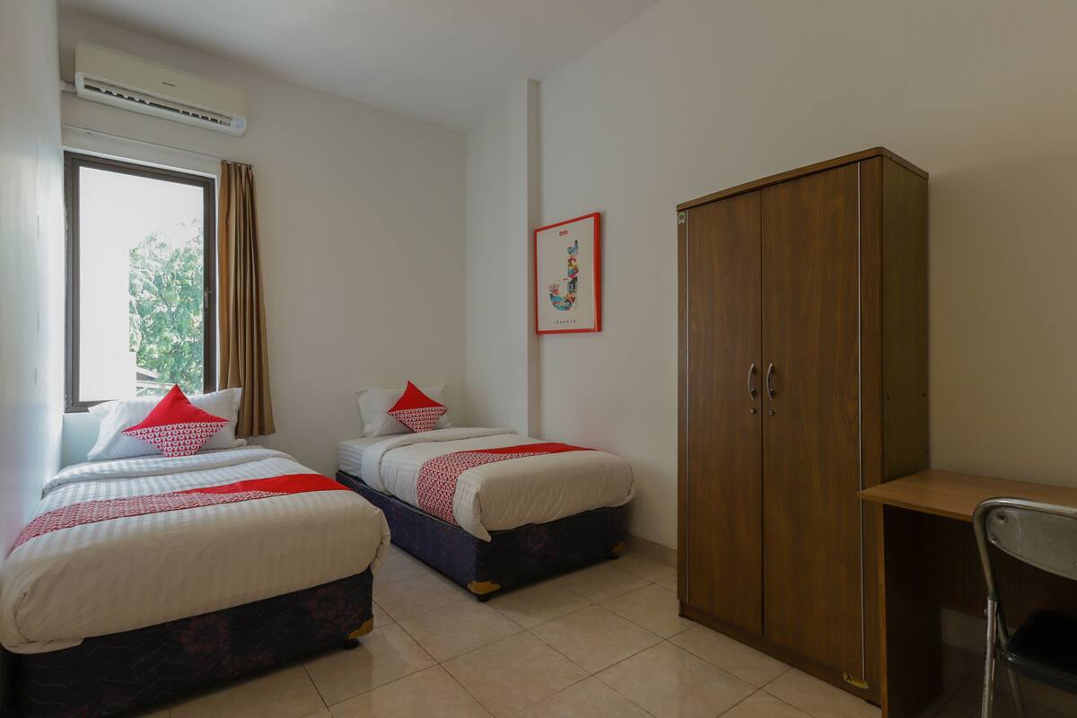 Une chambre avec deux lits, une armoire et un bureau.
