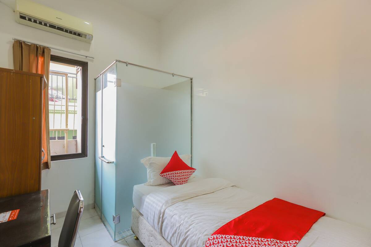Une chambre à coucher avec un lit, une armoire, un bureau et une fenêtre avec des rideaux.