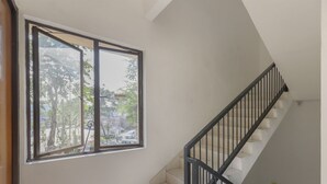 Un escalier avec une rampe noire et une fenêtre sur laquelle est apposé un panneau « Il est interdit de fumer ».