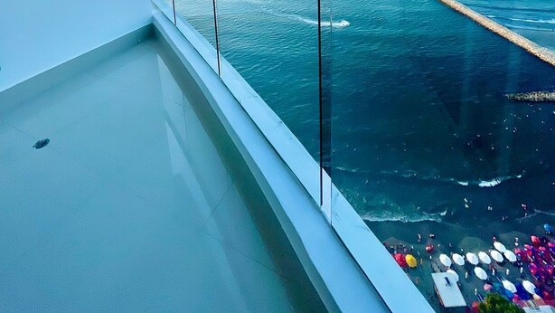 Un balcón con vistas despejadas al mar y un muelle distante.