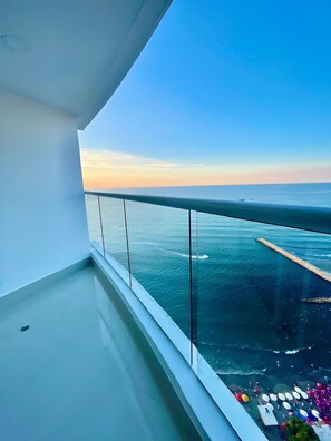 A balcony with a clear view of the sea and a distant pier.