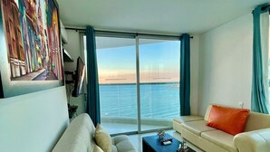 Una sala de estar moderna con un sofá, una mesa de centro y vista al mar a través de amplios ventanales.