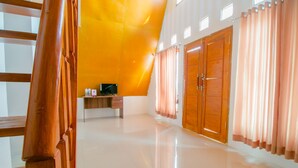 Una habitación amplia con techo alto, un armario de madera, un escritorio pequeño con una computadora y un ventanal con cortinas.