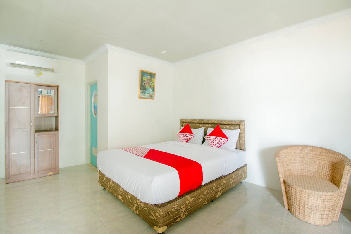 A bedroom with a bed, a wardrobe, a chair, and a painting on the wall.