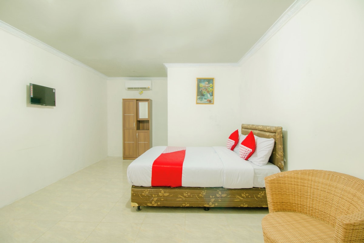 A hotel room with a bed, a television, a wardrobe, and a painting on the wall.