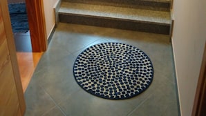 Una escalera con una planta en el rellano, una ventana arriba y una alfombra estampada abajo.