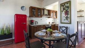 Uma cozinha moderna com armários de madeira, uma geladeira vermelha e uma área de refeições com cadeiras de vime e uma mesa de vidro.