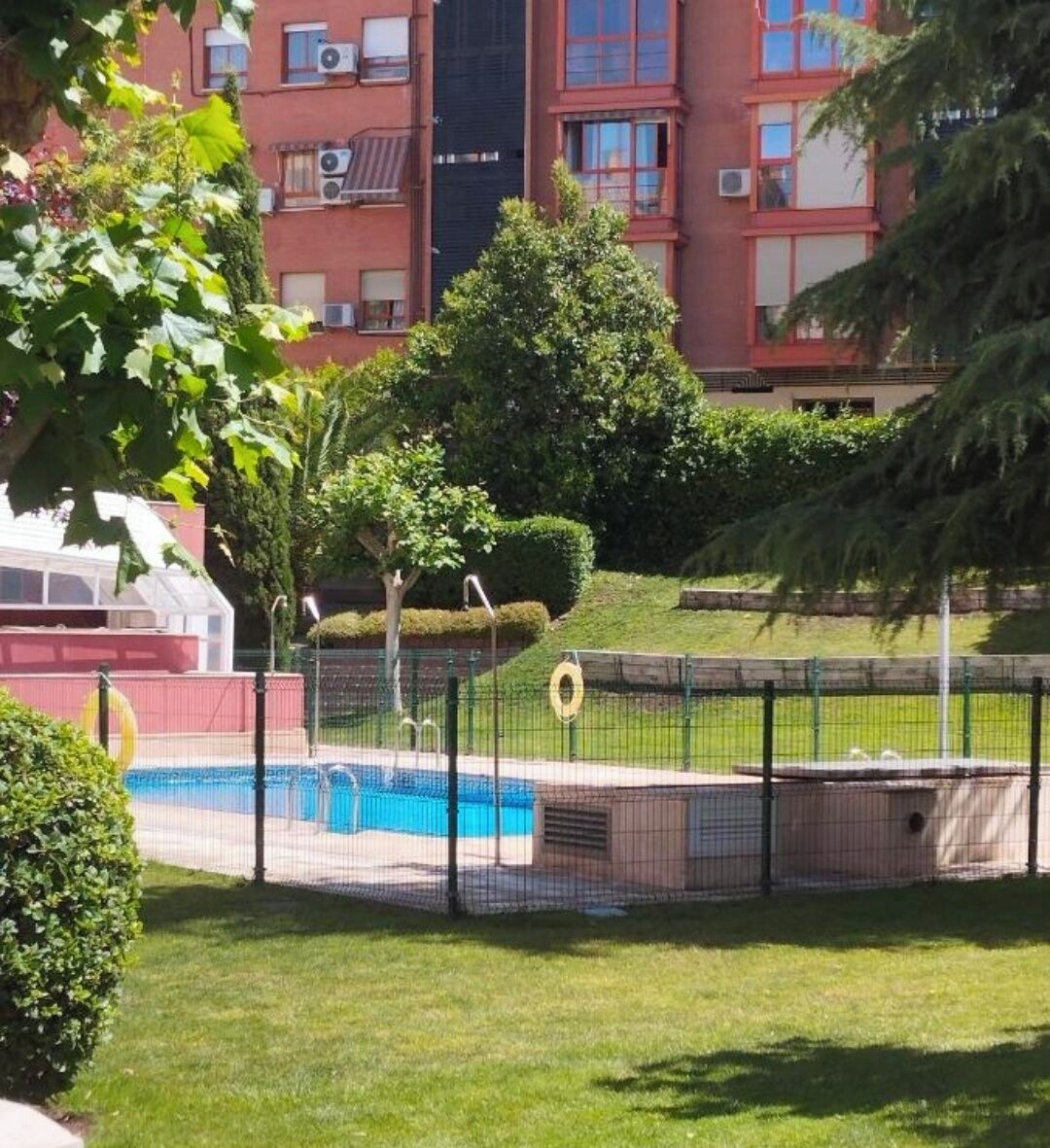 A swimming pool surrounded by a fence, with a building in the background.
