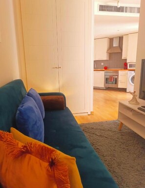 A living room with a sofa, a television, and a kitchen in the background. - FRIDDA HOUSE ATOCHA STATION MADRID (Madrid)