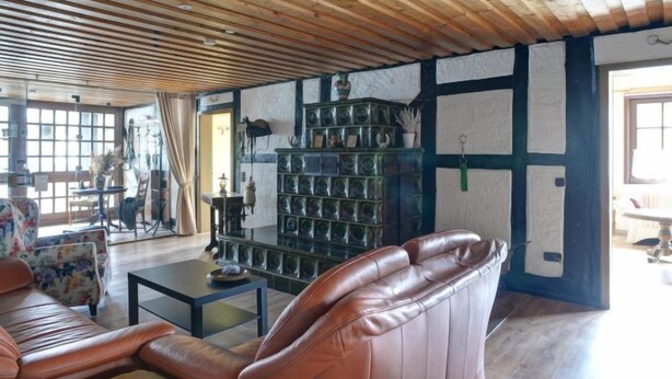A cozy living room with a wooden ceiling, a leather sofa, a coffee table, and a decorative cabinet. - An der Dorfkirche by Interhome (Hehlen)