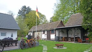 A rustic outdoor area with a stone pathway, a wooden bench, and a flagpole with a flag. - An der Dorfkirche by Interhome (Hehlen)
