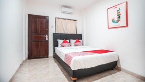 Una camera da letto con un letto, una porta, un condizionatore d'aria e un quadro appeso al muro.