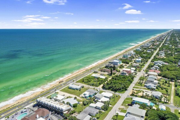 Vista aérea de una zona residencial costera con casas, una playa y una carretera.