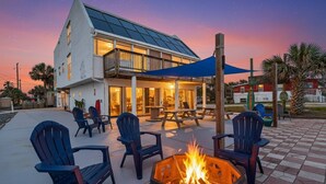 A building with a patio area featuring outdoor seating and a fire pit. - Pelican Suite | Bombora Suites | Steps To Flagler Beach & Restaurants (Flagler Beach)