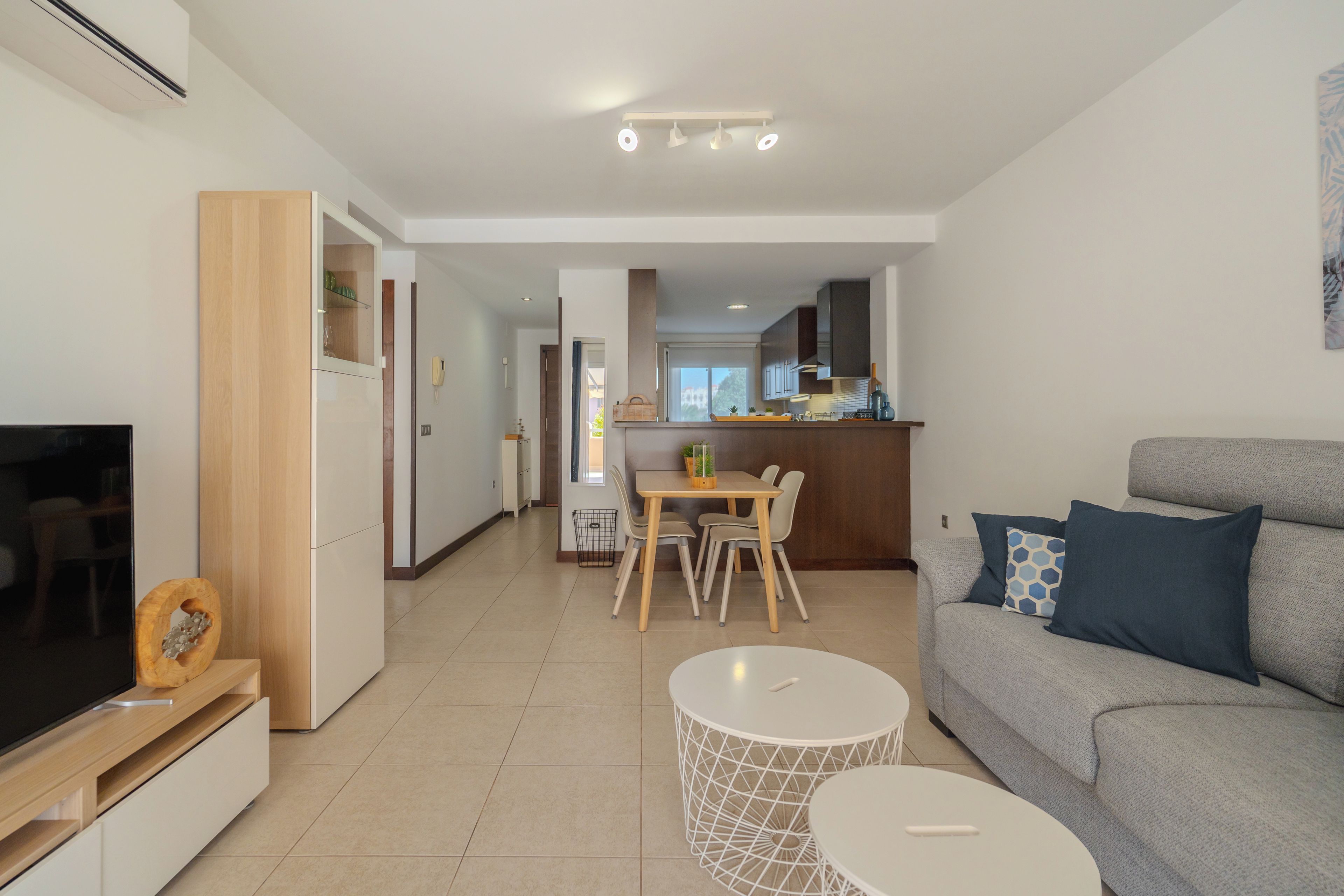 Un soggiorno moderno con un divano grigio, una TV e un'area pranzo con tavolo e sedie.
