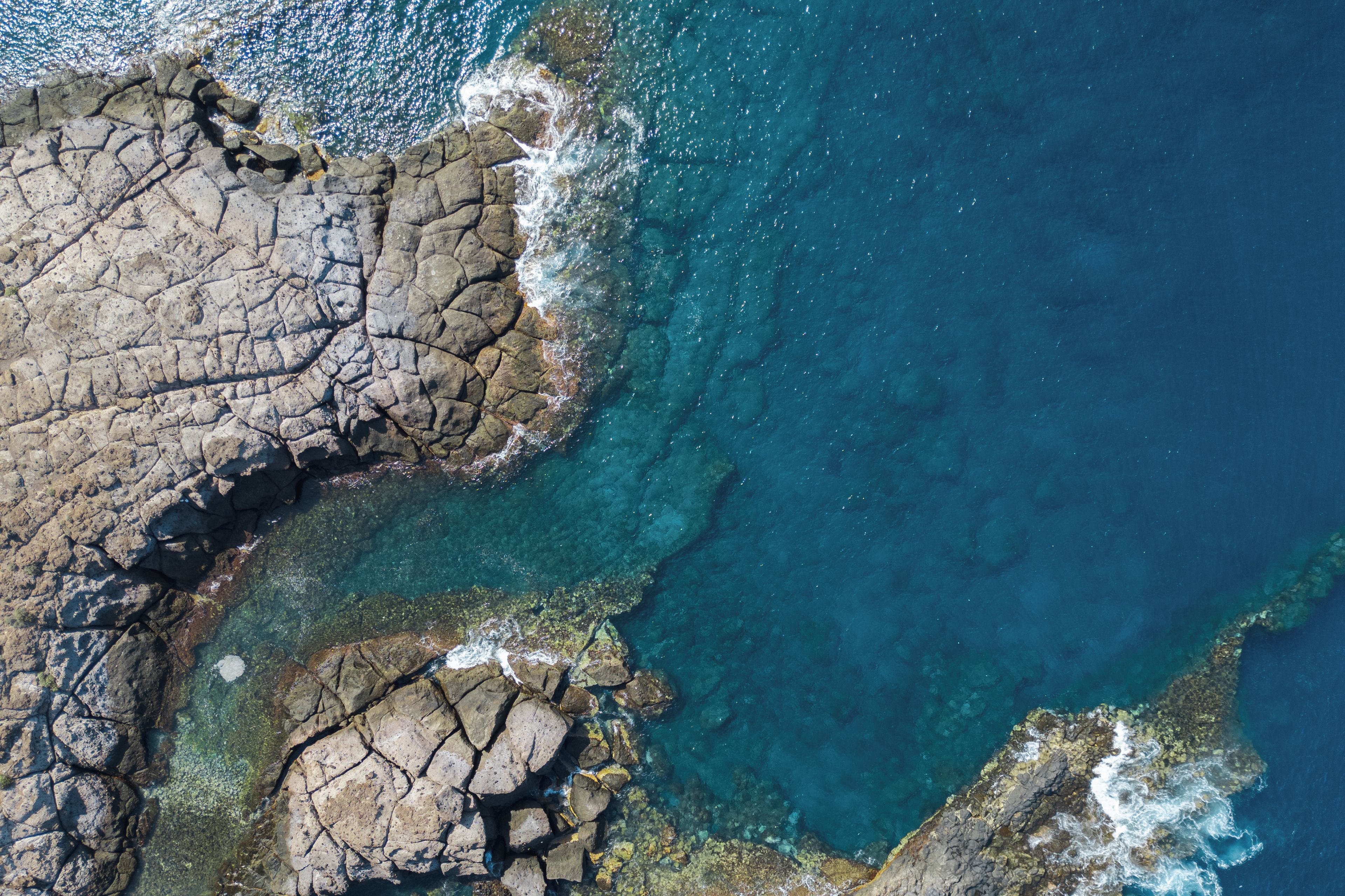 A coastal landscape with rocky terrain and clear blue waters.