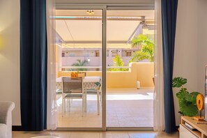A room with a sliding glass door leading to an outdoor area with a table, chairs, and a plant.