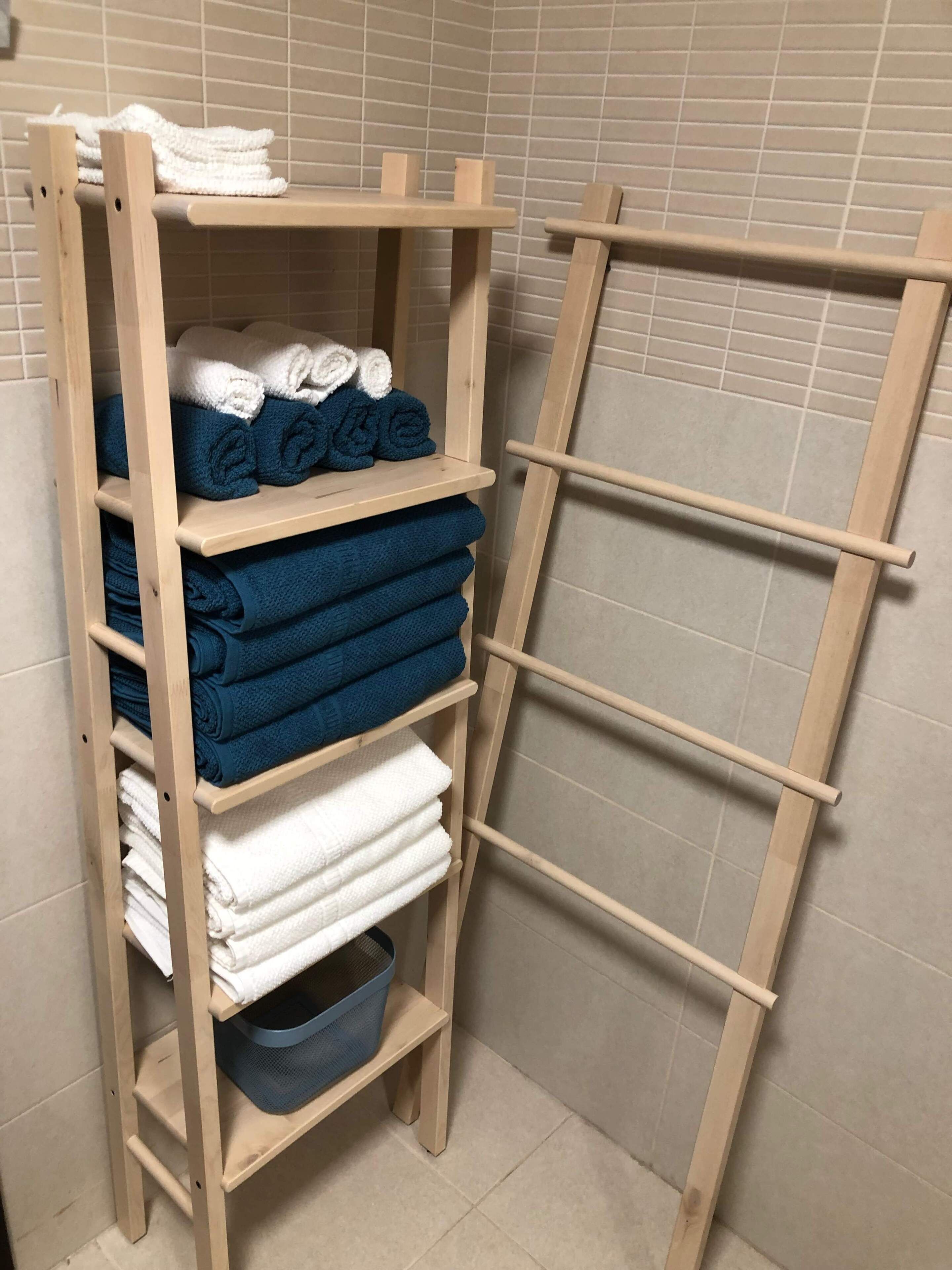 A wooden shelf unit with multiple tiers, each holding folded towels in white and blue.
