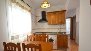 Una cucina compatta con un tavolo da pranzo, sedie, una lavatrice e mobili in legno.