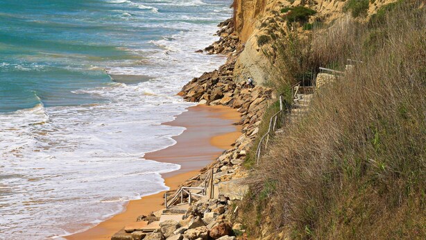 Una spiaggia costiera con scogliere rocciose e un litorale sabbioso.