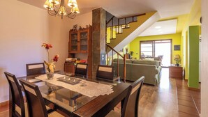 A dining area with a glass table, chairs, and a chandelier. There is a staircase leading to a living area with a sofa and a green wall. - GC0366 House with heated pool in El Valle de Agaete (Agaete)