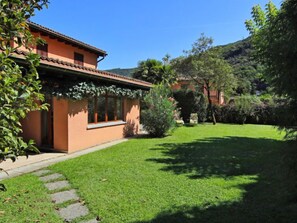 A house with a garden, a stone pathway, and a hill in the background. - Casa Riva by Interhome (Figino)