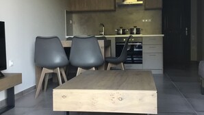 Una cocina moderna con armarios de madera, horno empotrado y comedor con mesa y dos sillas de madera.